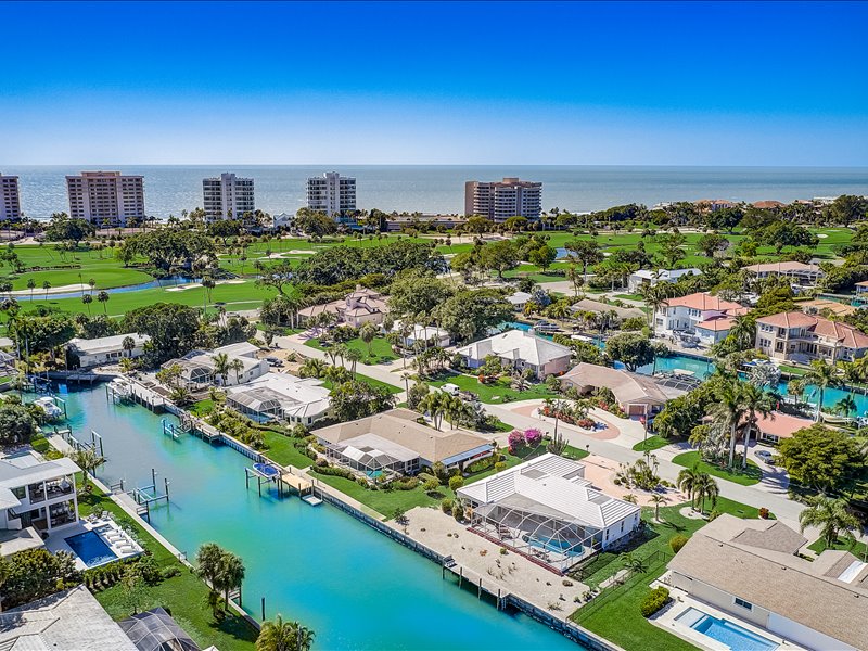 An arial view of the Country Club Shores Neighborhoods showing homes lining a canal. To the left are condos lining the Gulf of Mexico.