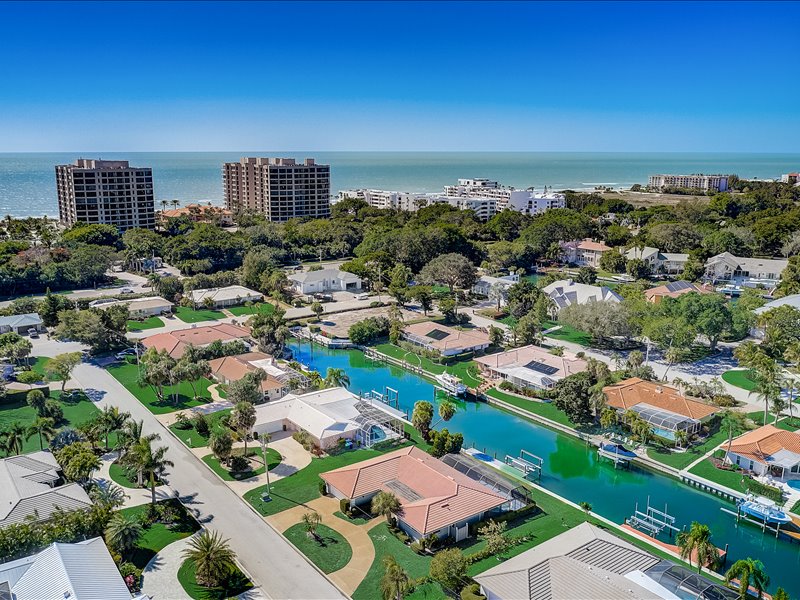 An aerial view of the Country Club Shores Neighborhoods showing homes lining a canal. To the left are condos lining the Gulf of Mexico.