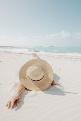 a Florida tourist wearing a straw sun hat laying on the beach
