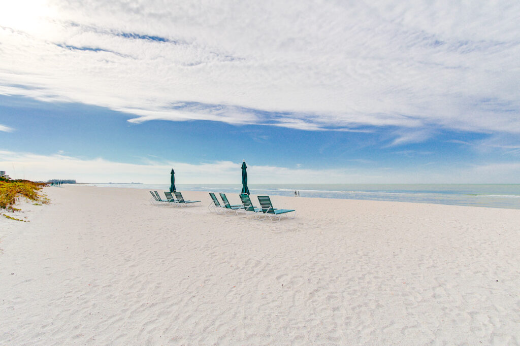 A photo of the white sand beach with baby blue umbrellas for Sanctuary Longboat Key residents