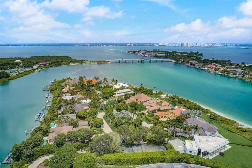 Aerial view of Lighthouse Point in Longboat Key depicting the private cove of homes with sweeping views of the Gulf of Mexico and the New Pass Bridge.